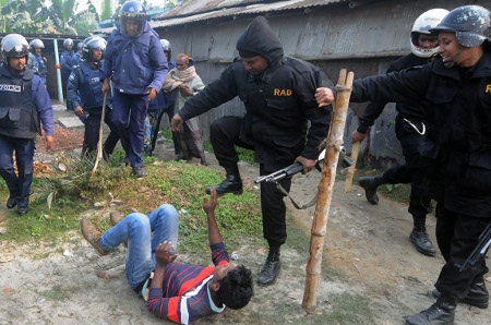 En polis från fruktade RAB misshandlar en person som misstänks ha attackerat en polisstation i Bogra den 5 januari 2014.