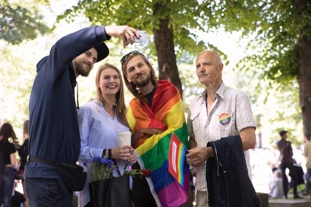 Emils Libeks (till vänster) förevigar den 9 juni familjens första Prideparad tillsammans i Riga. I mitten syns Janis Libeks draperad i regnbågsflagga mellan broderns flickvän Ieva Barone och pappa Andris.