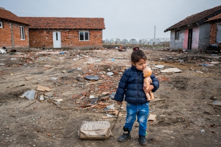 Tvååriga Miela Yordanova med sin ryggsäck och docka när de lämnar den bosättning som har varit de romska familjernas hem i decennier. 