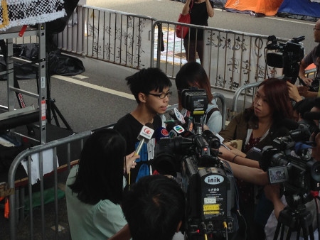 Joshua Wong håller presskonferens under Paraplyrörelsens protester 2014. Då var fokus krav på ökad demokrati i Hongkong. Den 29 oktober 2019 förbjöd myndigheterna Joshua Wong att ställa upp som kandidat i ett lokalval. 